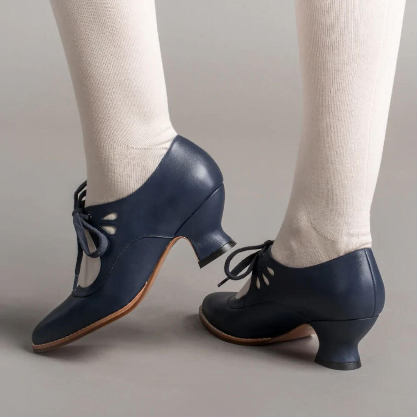 Elegante marineblaue Lederpumps mit Vintage-Cut-outs und Schnürverschluss, ideal für ein Retro-Outfit.