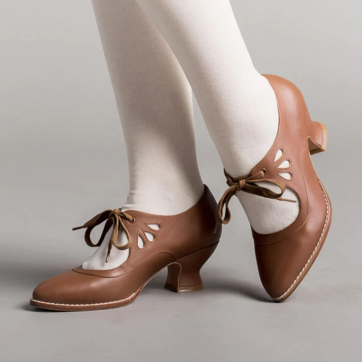 Klassische braune Lederschnürpumps mit filigranen Cut-outs, ein zeitloser Vintage-Stil.