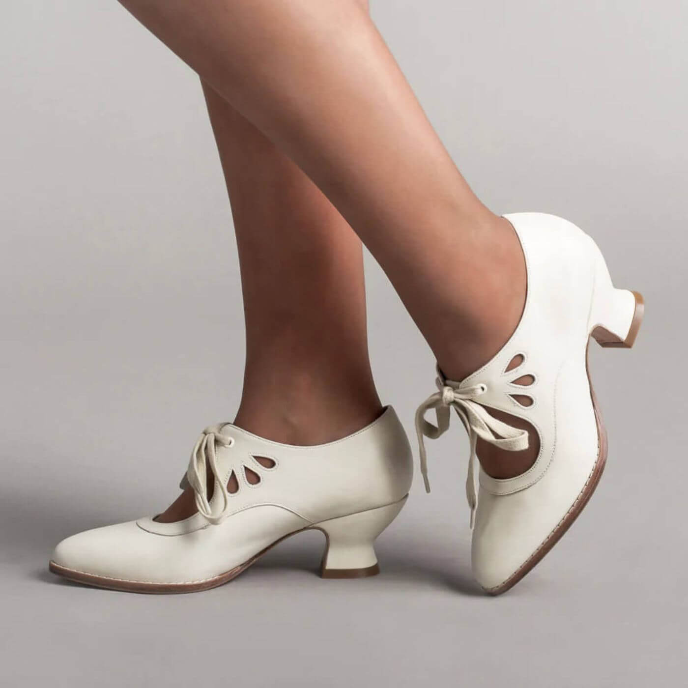 Schicke weiße Lederpumps mit Schnürung und filigranen Cut-outs, perfekt für einen eleganten Retro-Look.