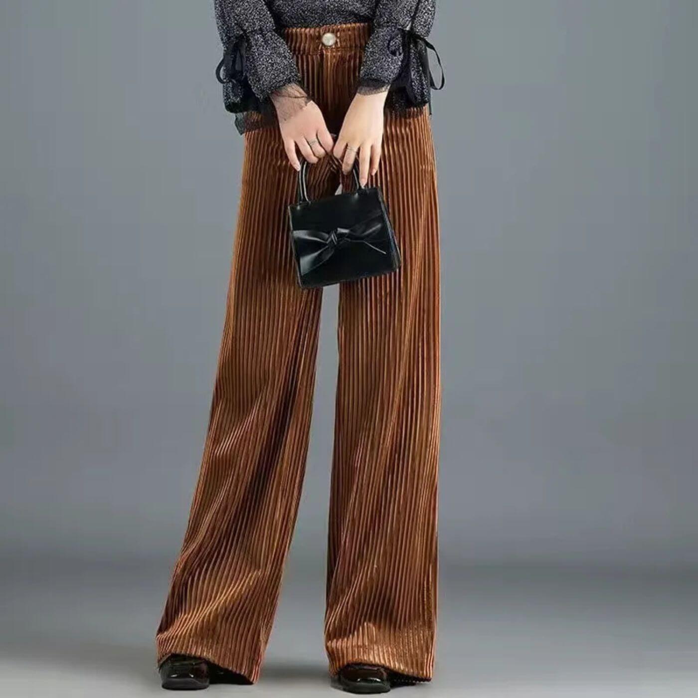 Pantalon large en velours côtelé marron associé à un sac à main chic.