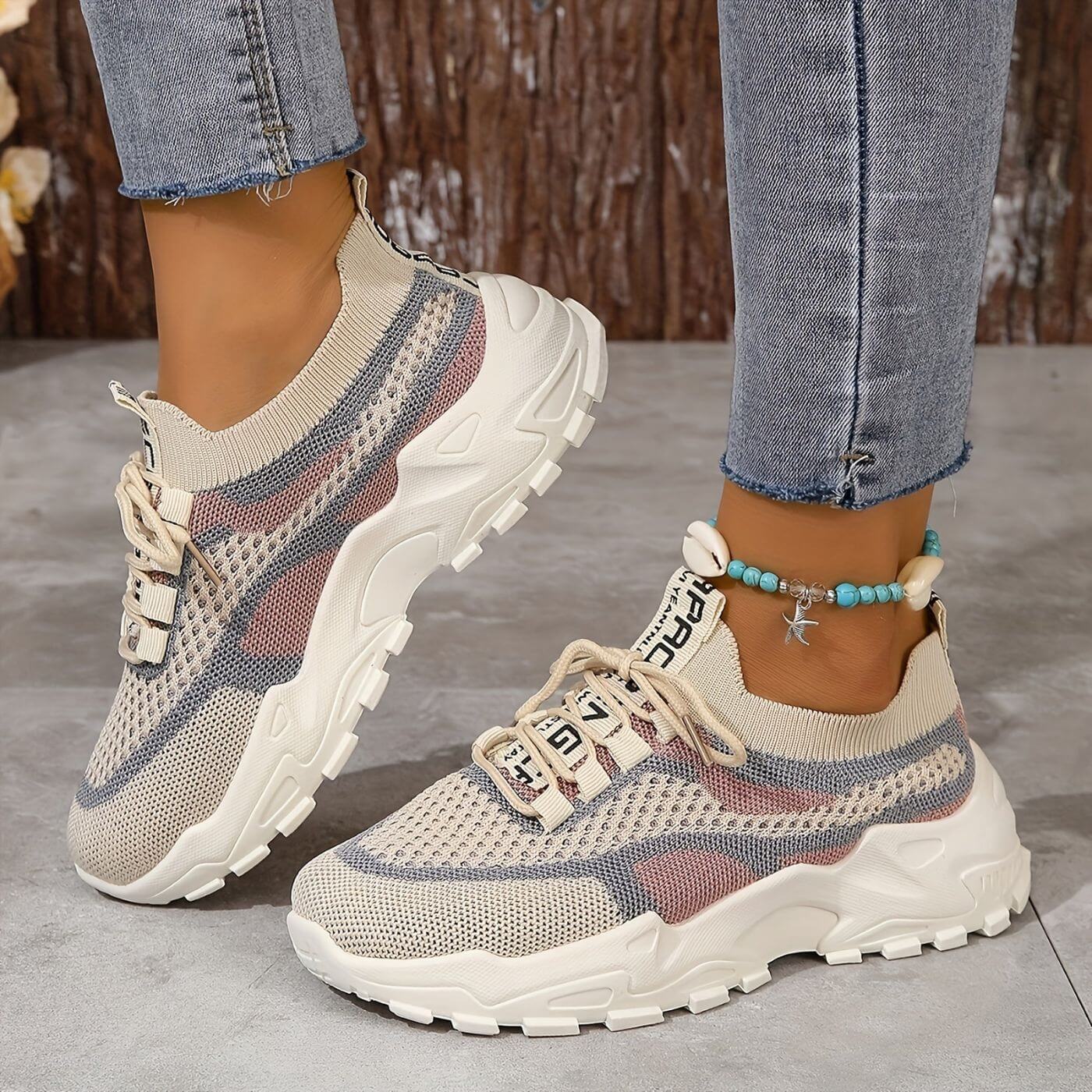 Beige-rosa Sneaker mit Muschelkettchen auf Holzboden