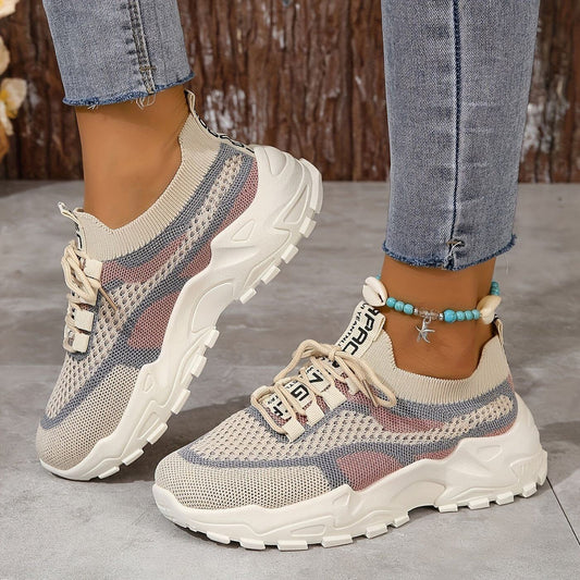 Beige-rosa Sneaker mit Muschelkettchen auf Holzboden